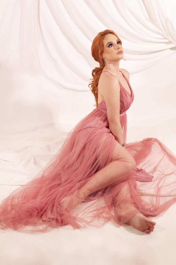 Modelo con vestido rosa transparente posando con fondo de telas